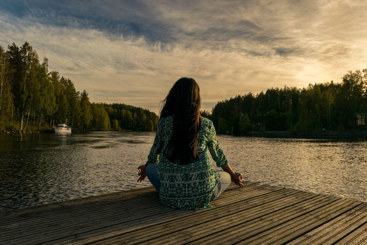 Mulher meditando em píer.