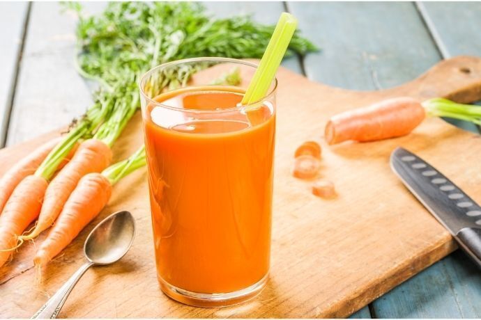 Suco de cenoura e cenouras cortadas sobre tábua de madeira