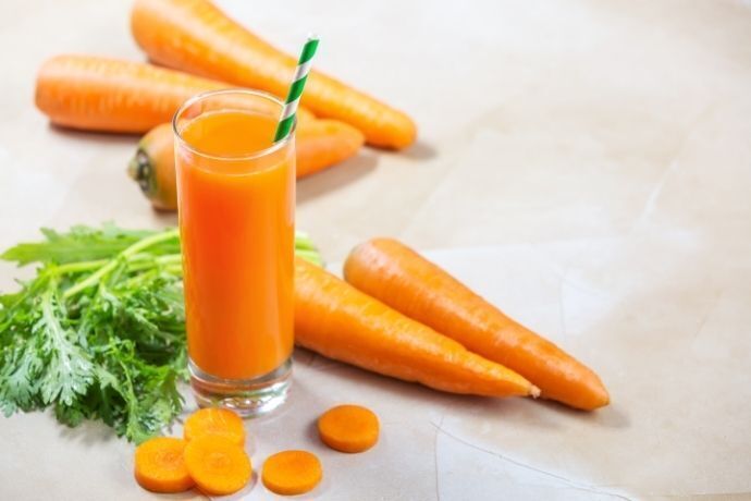 Copo com suco de cenoura e cenoura cortada em rodelas