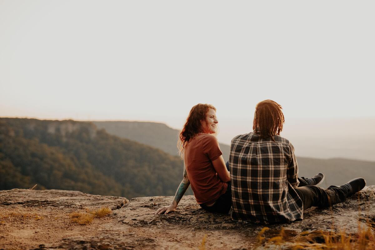 Casal de amigos observando a paisagem do alto de uma montanha. 