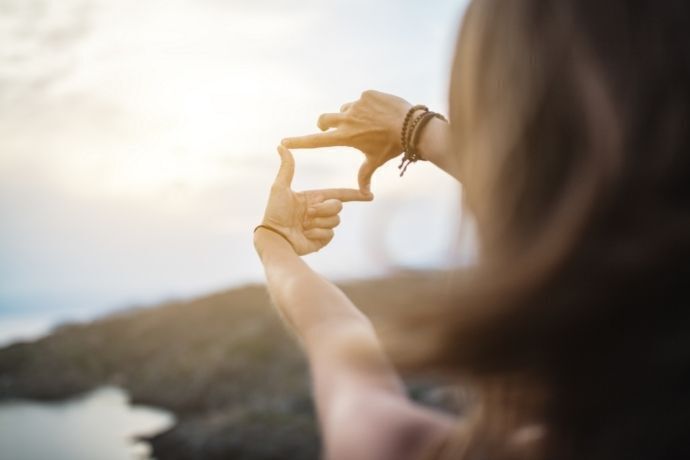 Mulher fazendo sinal de foco para paisagem