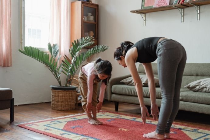 Mãe e filha fazendo alongamentos na sala