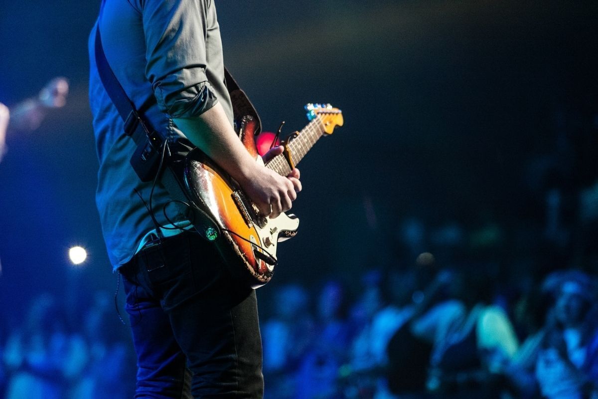 Homem tocando guitarra em show.