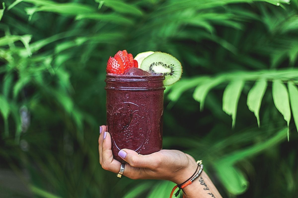 Mulher segurando copo com açaí.