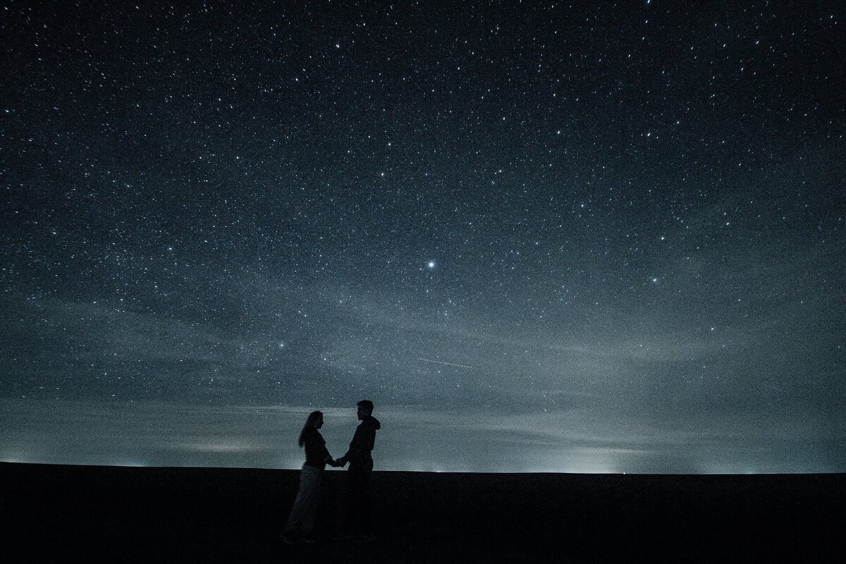 Casal sob céu estrelado. 