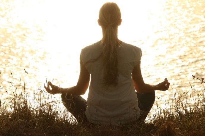 Mulher meditando em frente a um lago