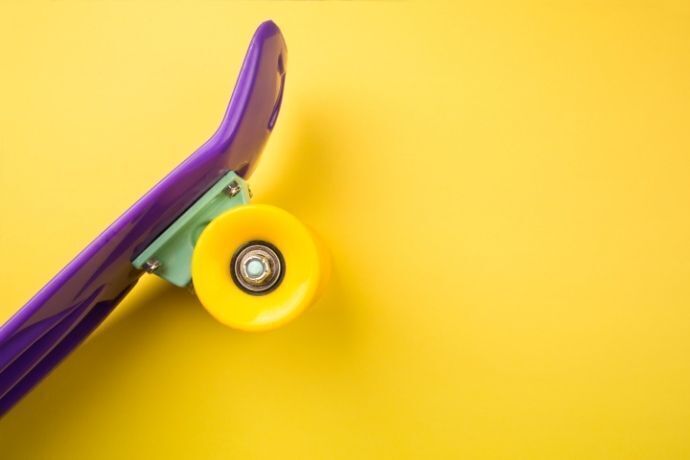 Skate roxo com rodas amarelas em fundo amarelo