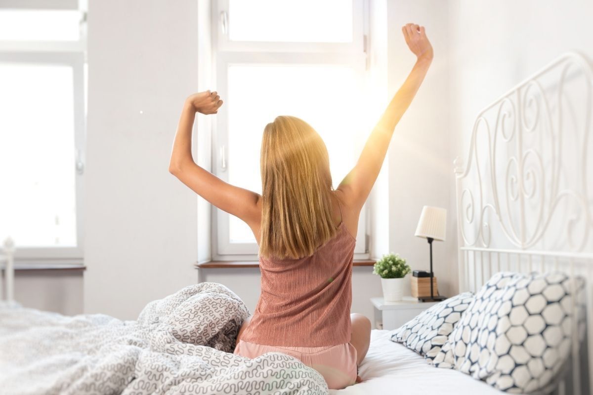 Mulher acordando em sua cama.