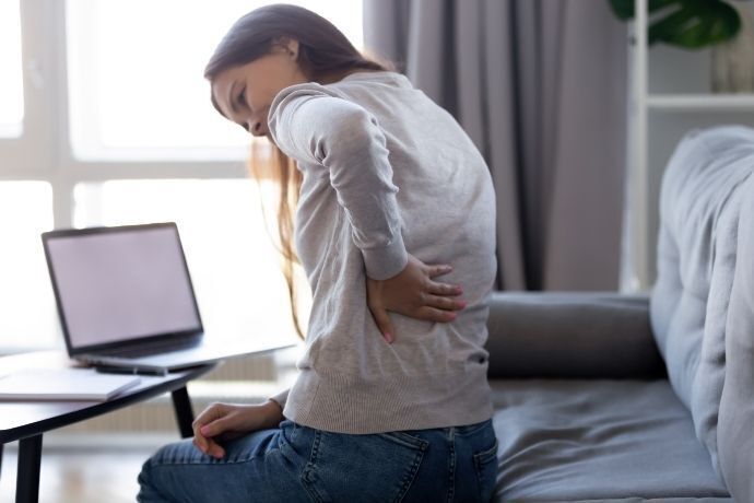 Mulher levantando do sofá com dor nas costas