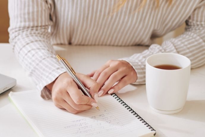 Mulher escrevendo afirmações positivas em um caderno