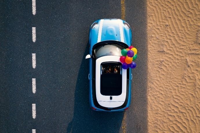 Carro azul visto de cima em estrada ao lado de praia