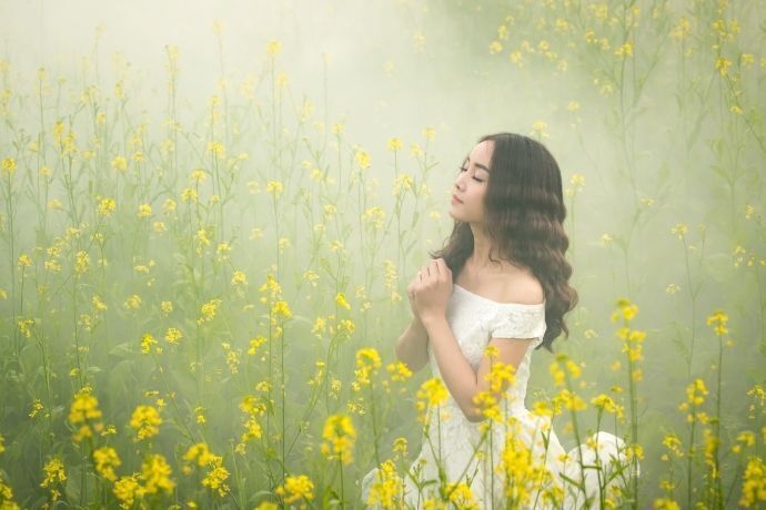 Mulher rezando em campo de flores