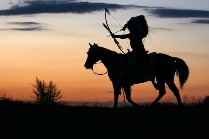 Silhueta de um índio em cavalo segurando arco e flecha