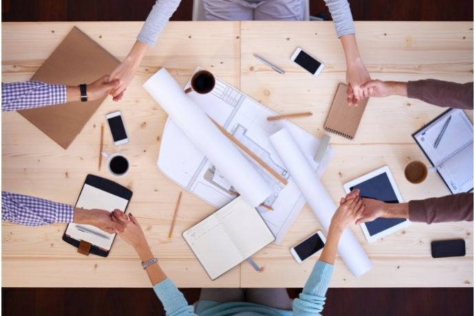 Pessoas de mãos dadas sobre a mesa rezando no trabalho