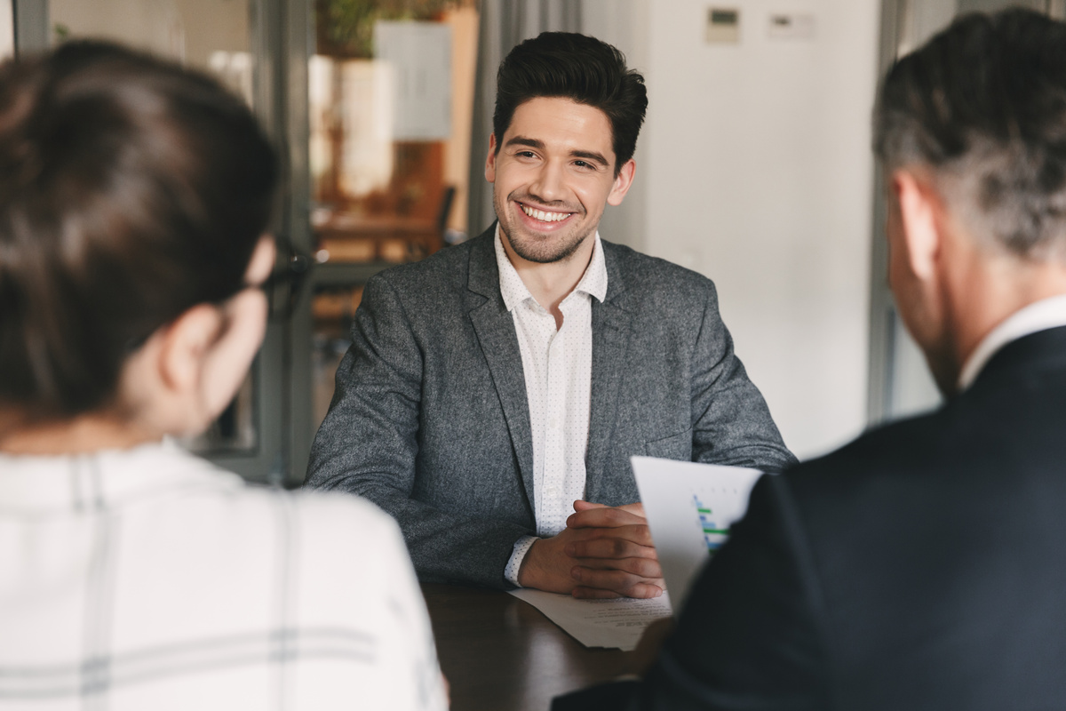 Homem satisfeito, sorrindo para contratadores durante sua entrevista de emprego.