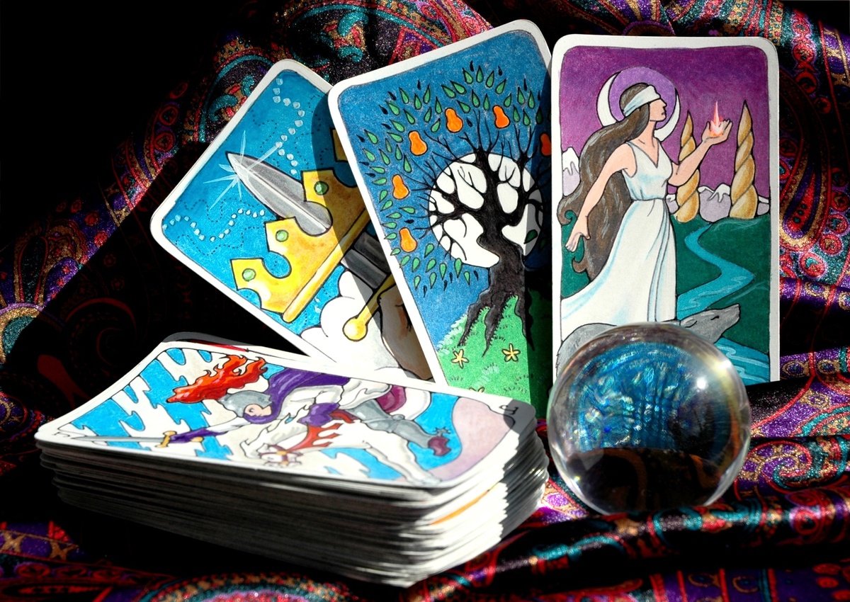 Carta Ás de Espadas enfileirada com outras do Tarot, acompanhadas de globo transparente e em meio a cenário estampado.