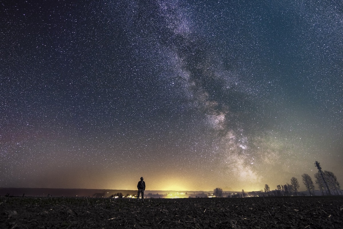 Homem observando o céu estrelado. 