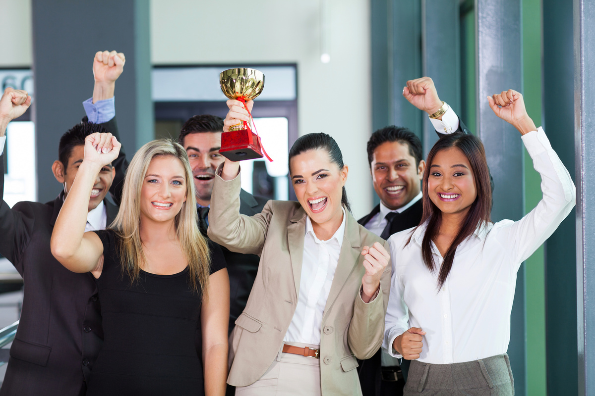 Mulher levantando um troféu e pessoas comemorando.