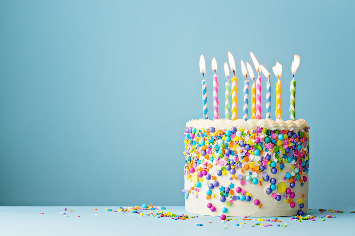 Bolo de aniversário com chantilly, enfeites e velas.