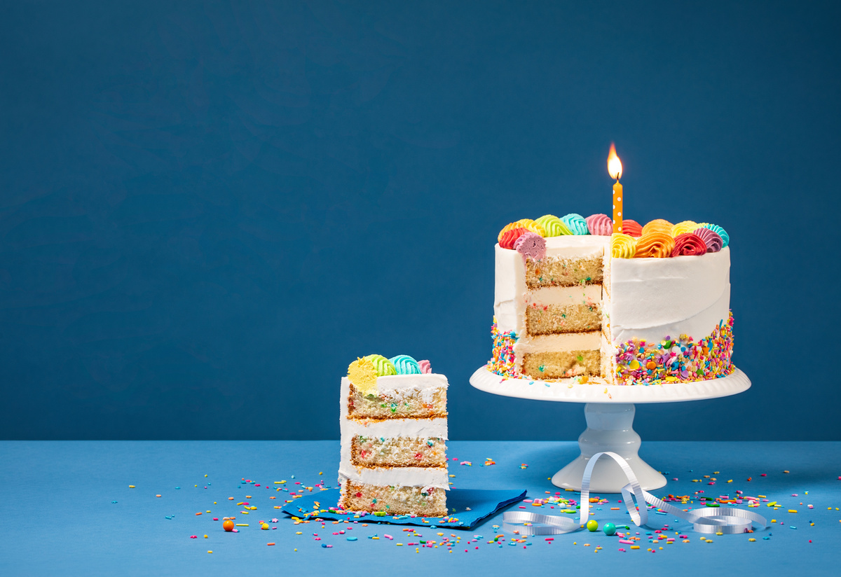 Bolo de aniversário com fatia cortada em um prato.