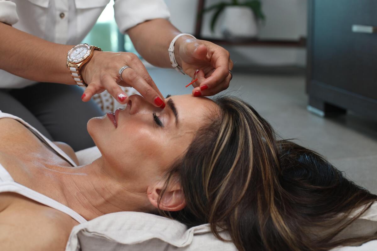 Mulher fazendo terapia Barra de Access, em que a terapeuta aplica toques pontos da sua cabeça. 