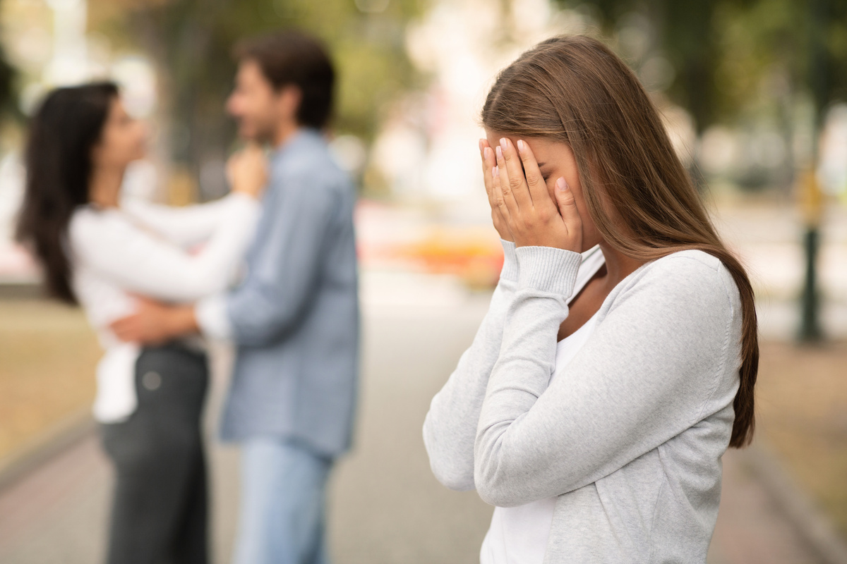 Mulher triste ao ver ex-namorado com outra.