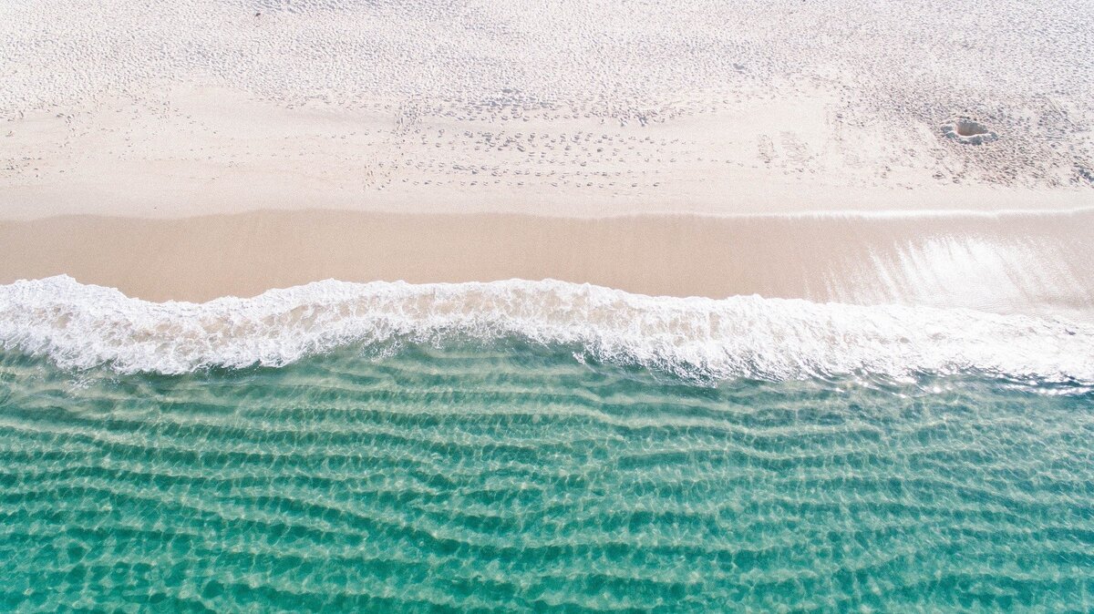 Vista aérea de praia com mar cristalino.