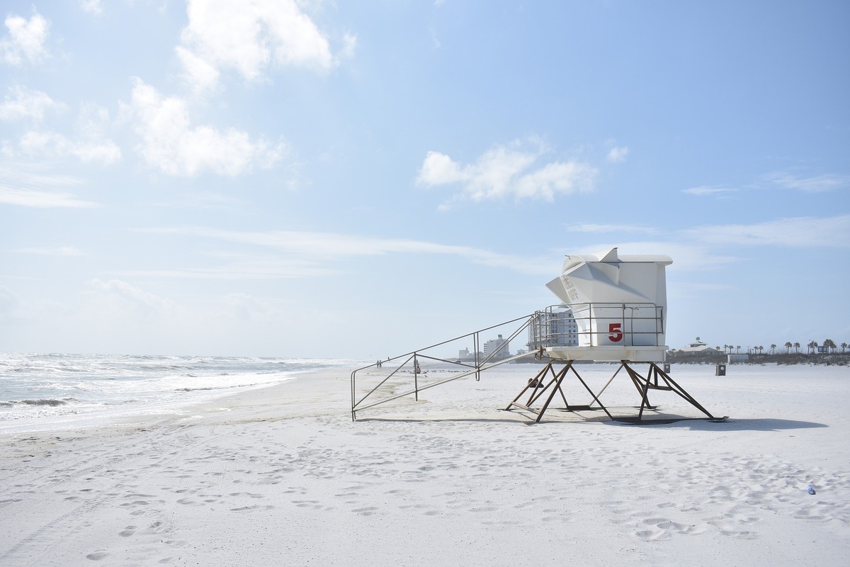 Cabine de salva-vidas na beirada de uma praia ensolarada.