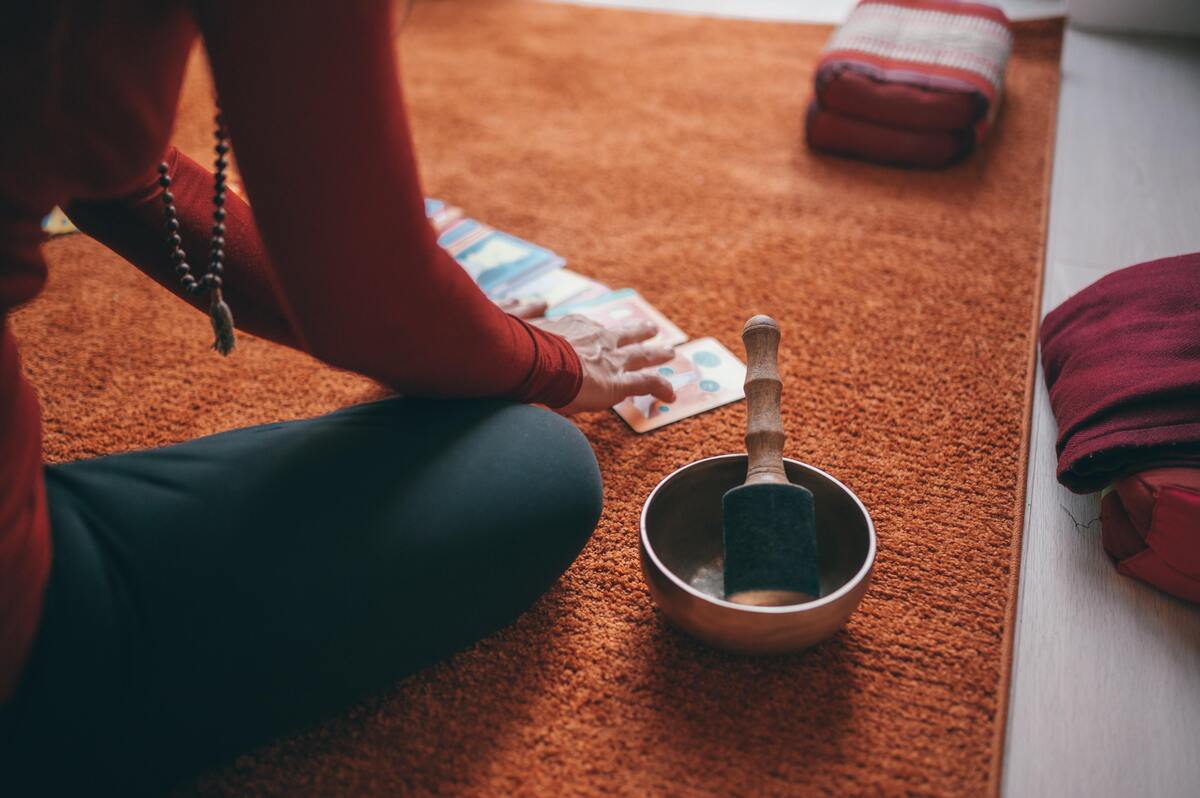 Mulher sentada ao chão consultado cartas de baralho cigano.