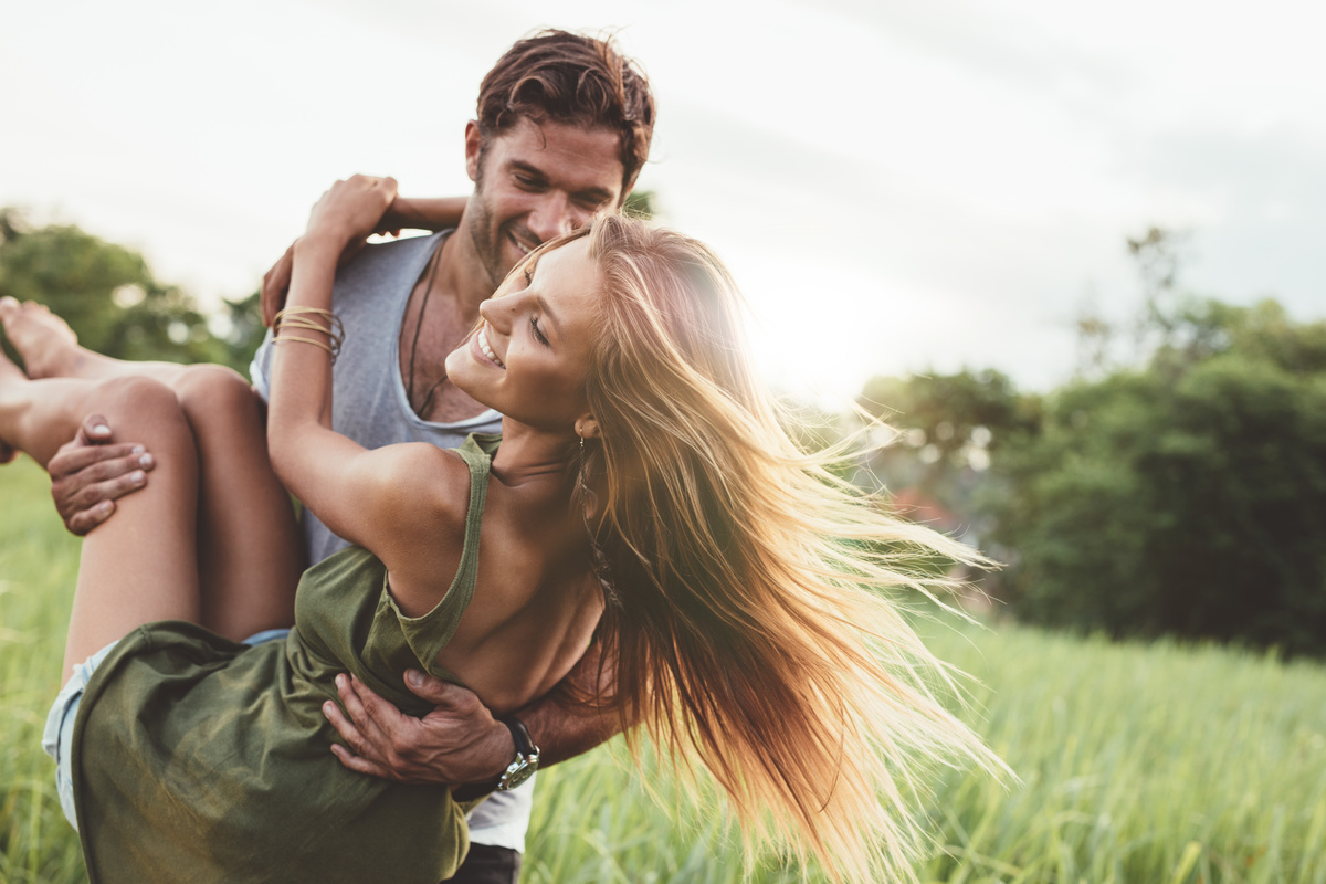 Homem carregando mulher no colo em meio a cenário de natureza, representando o homem de Libra como par romântico.