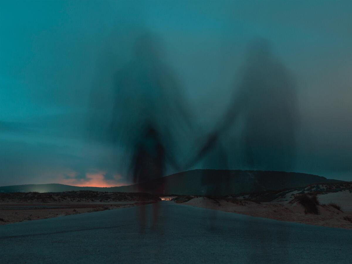 Sombras de pessoas andando em estrada de mãos dadas.