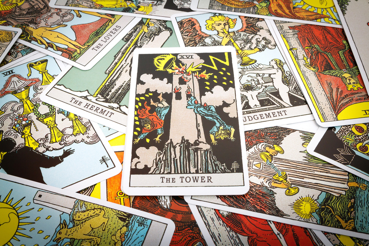 Cartas de tarot espalhadas por superfície, enquanto a carta A Torre está ao centro delas.