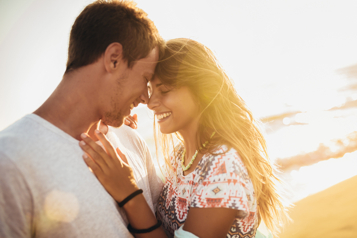 Casal sorrindo e se abraçando em praia