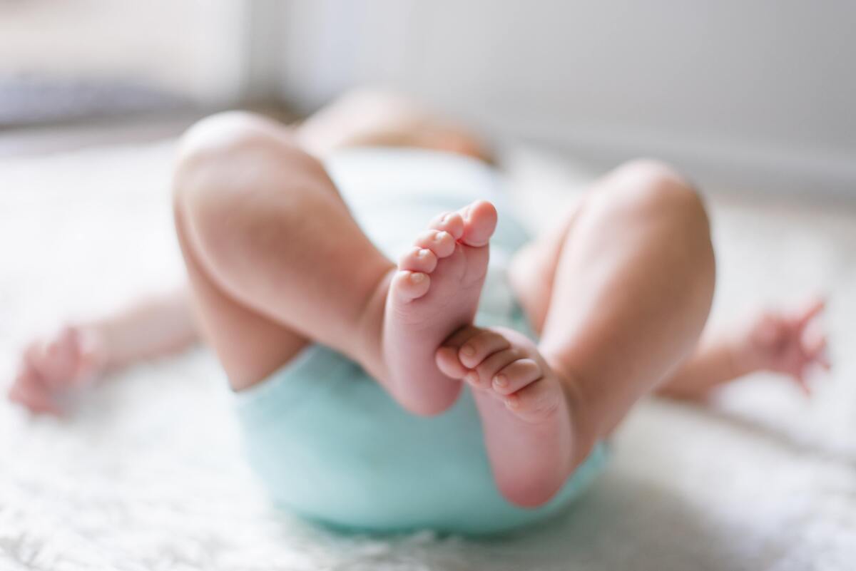 Bebê deitado com roupa azul.