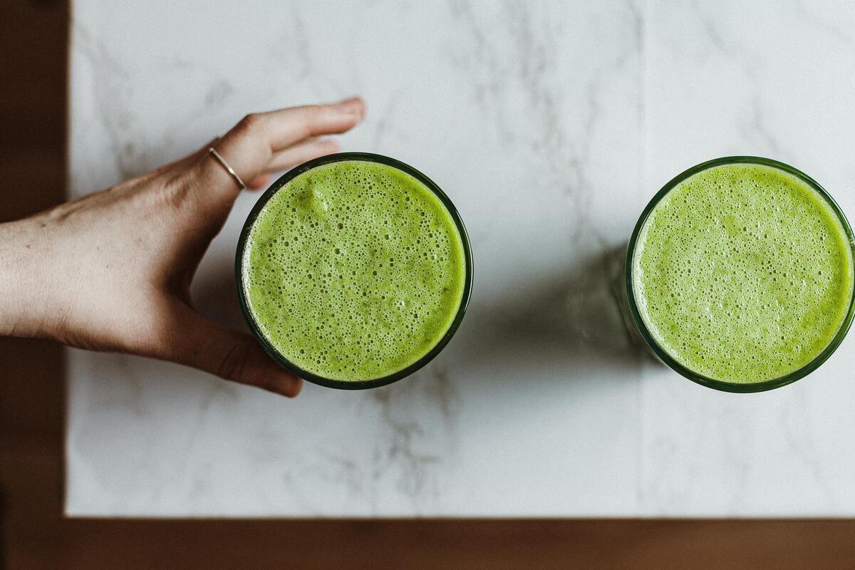 Dois copos de vidro com suco verde dentro.