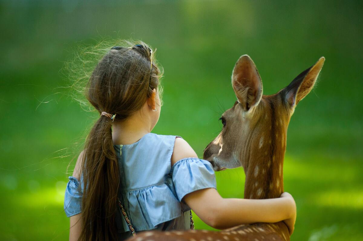 Menina abraçada com veado