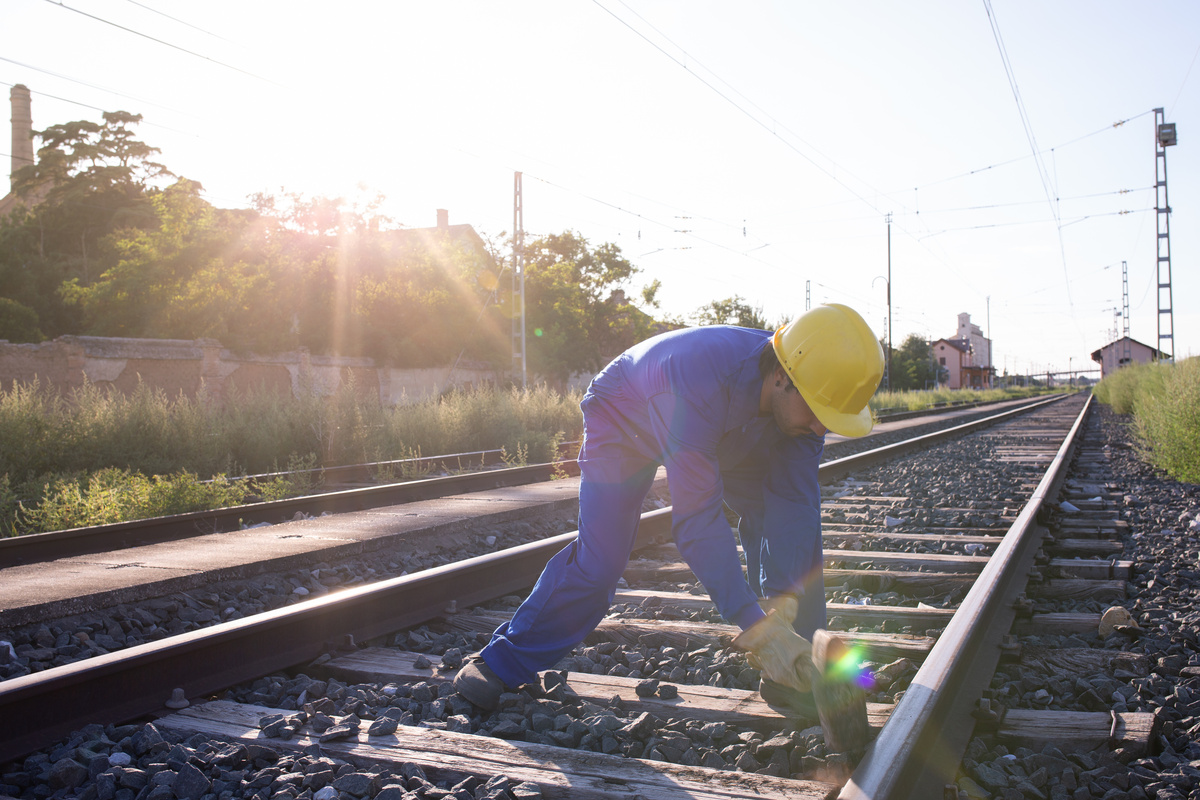 Homem consertando trilho de trem quebrado