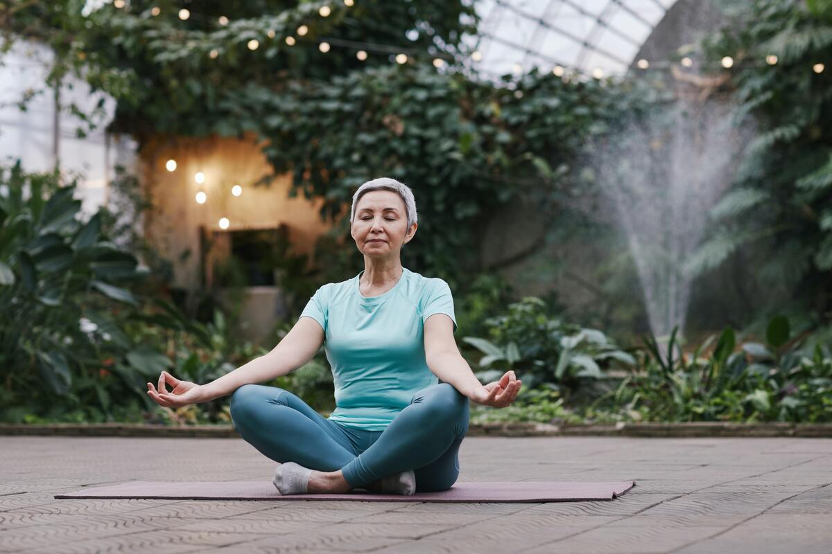 Senhora fazendo meditação no jardim