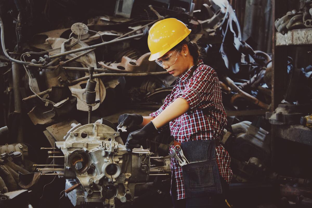 Mulher manuseando ferramentas enquanto usa um capacete de proteção.