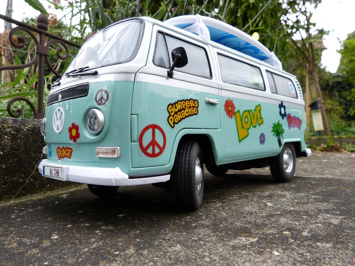 Lateral de Kombi azul-esverdeada com adesivos vintage colados em sua superfície.