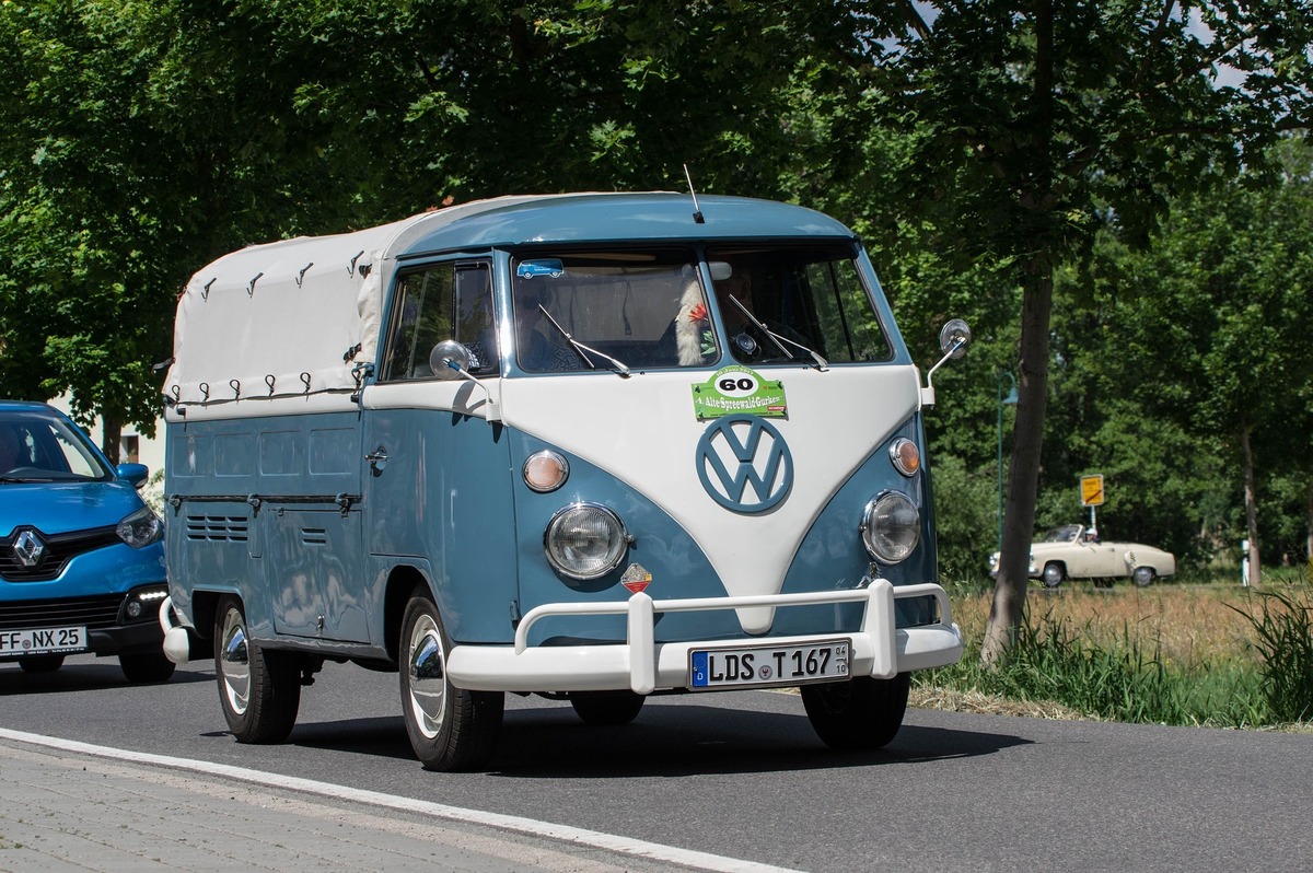 Kombi azul com detalhes em branco em meio da rua.