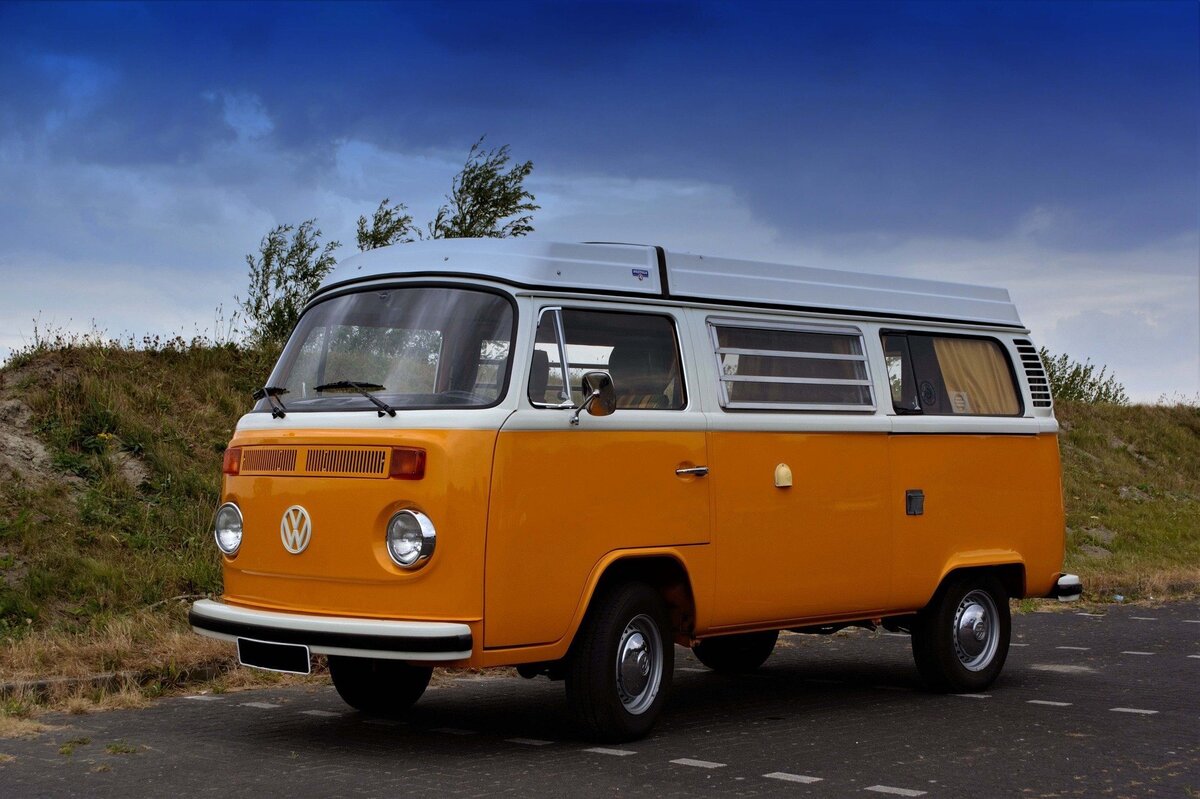 Kombi laranja estacionada em meio à estrada.