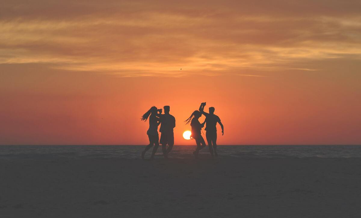 Silhueta de dois casais dançando na praia.