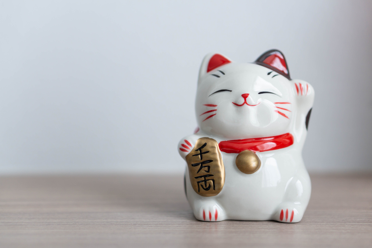 Pequena estátua branca de Maneki Neko, ou o Gato da Sorte.