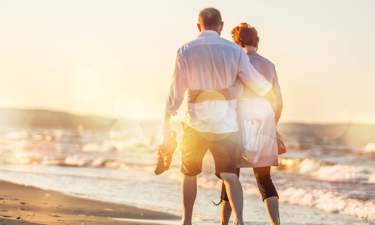 Casal de idosos caminhando pela praia.