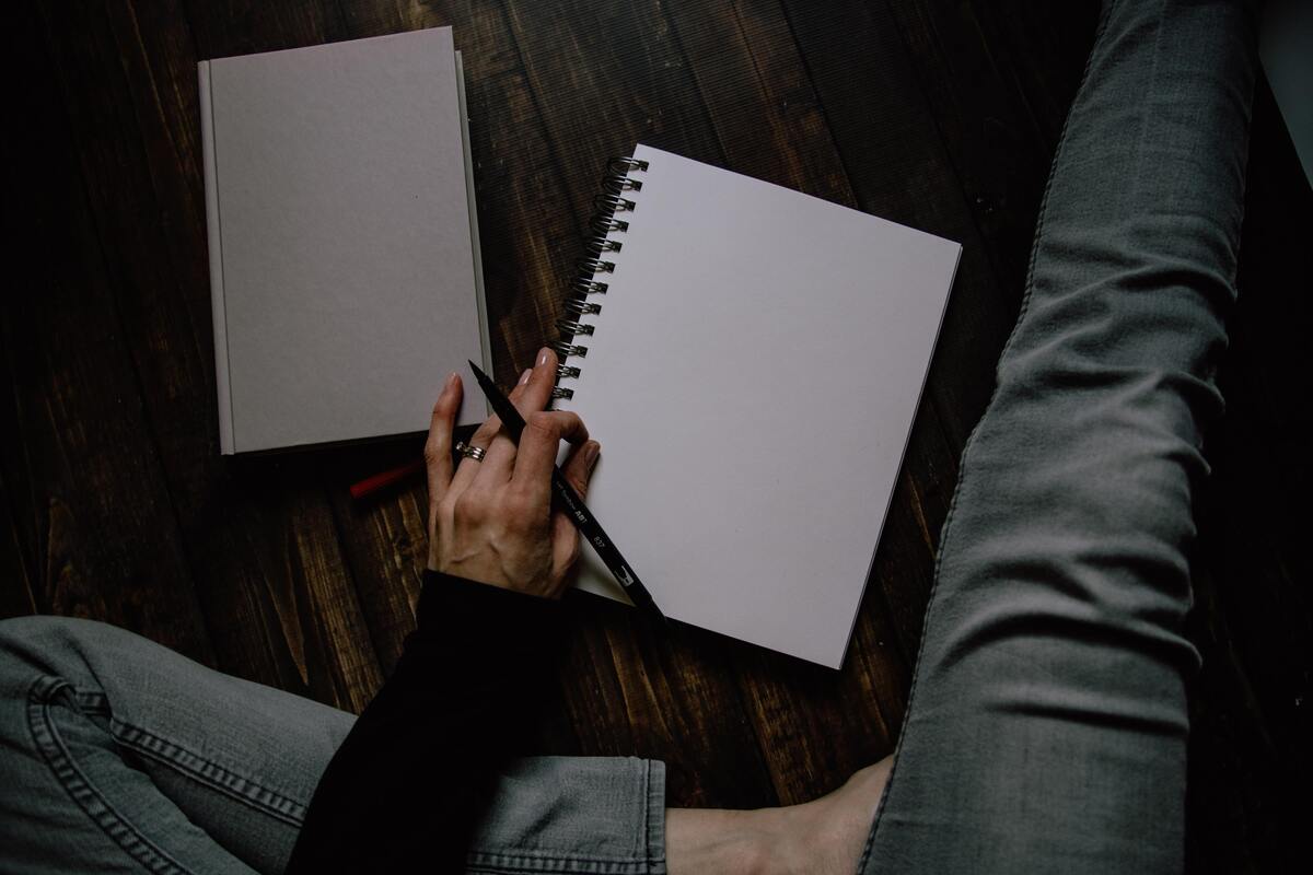 Pessoa com caneta e caderno em branco