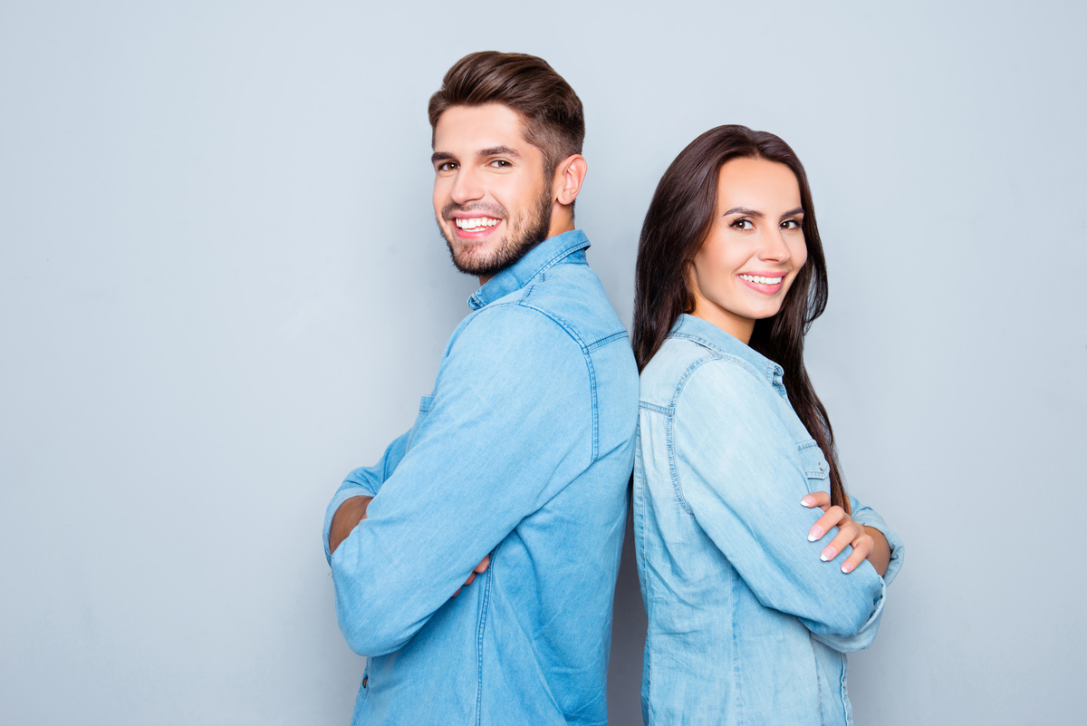 Homem e mulher posando de braços cruzados, um de costas para o outro, representando uma possível combinação de Touro com Aquário.