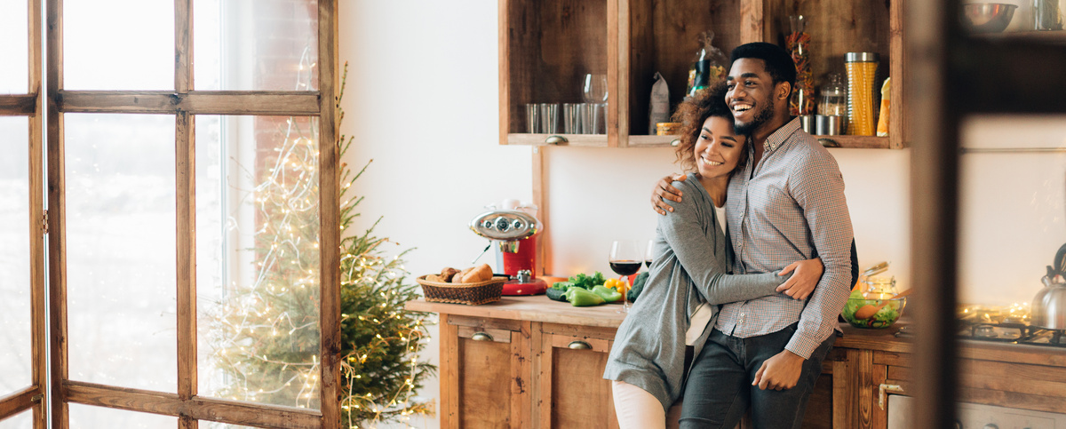 Homem e mulher abraçados sorrindo em cozinha