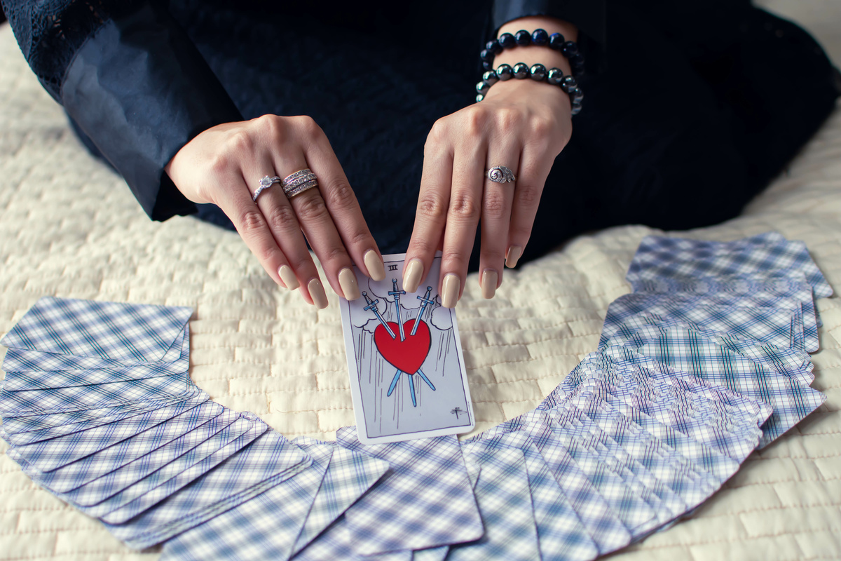 Mulher tirando a carta 3 de Espadas do Tarot