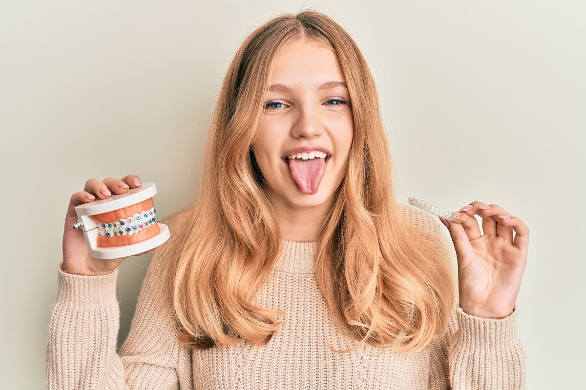 Menina segurando dentadura com aparelho